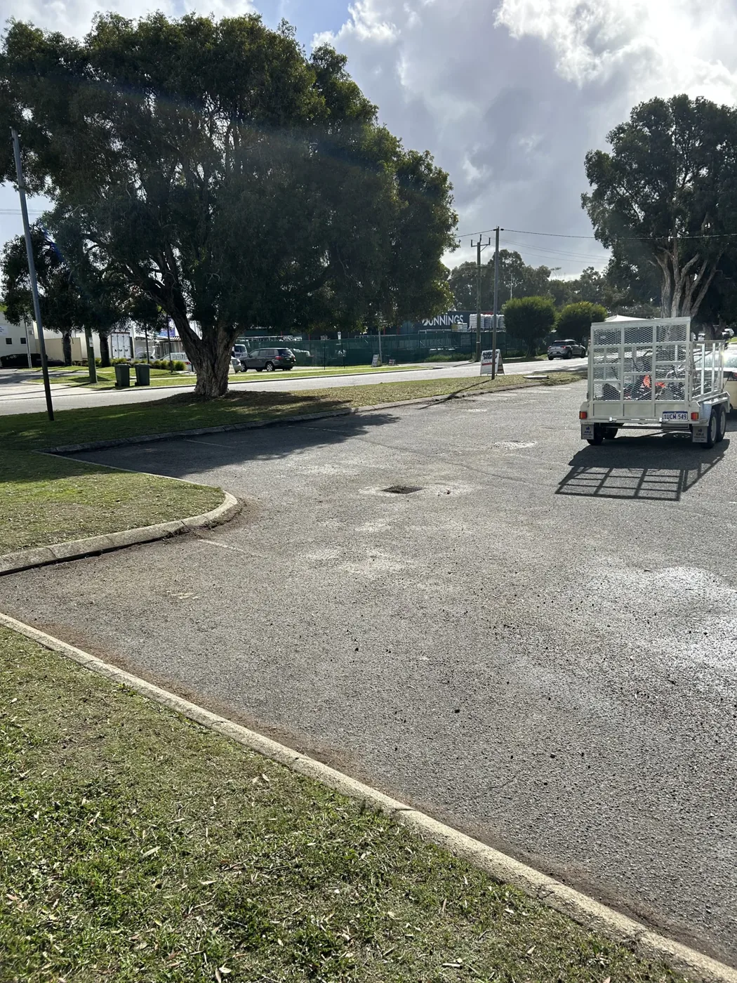 Work trailer parked beside a grass verge and paved access road
