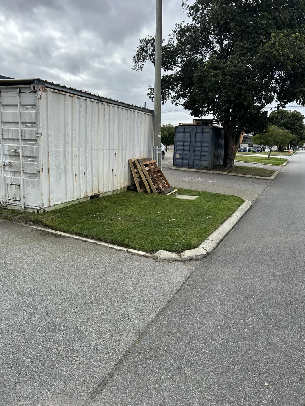 Grass verge with defined edges beside a driveway and storage containers